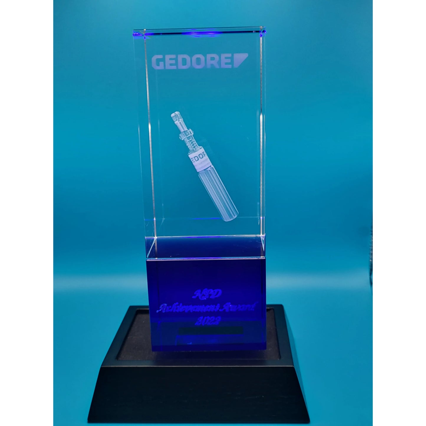 Clear glass award with engraved design on a blue background