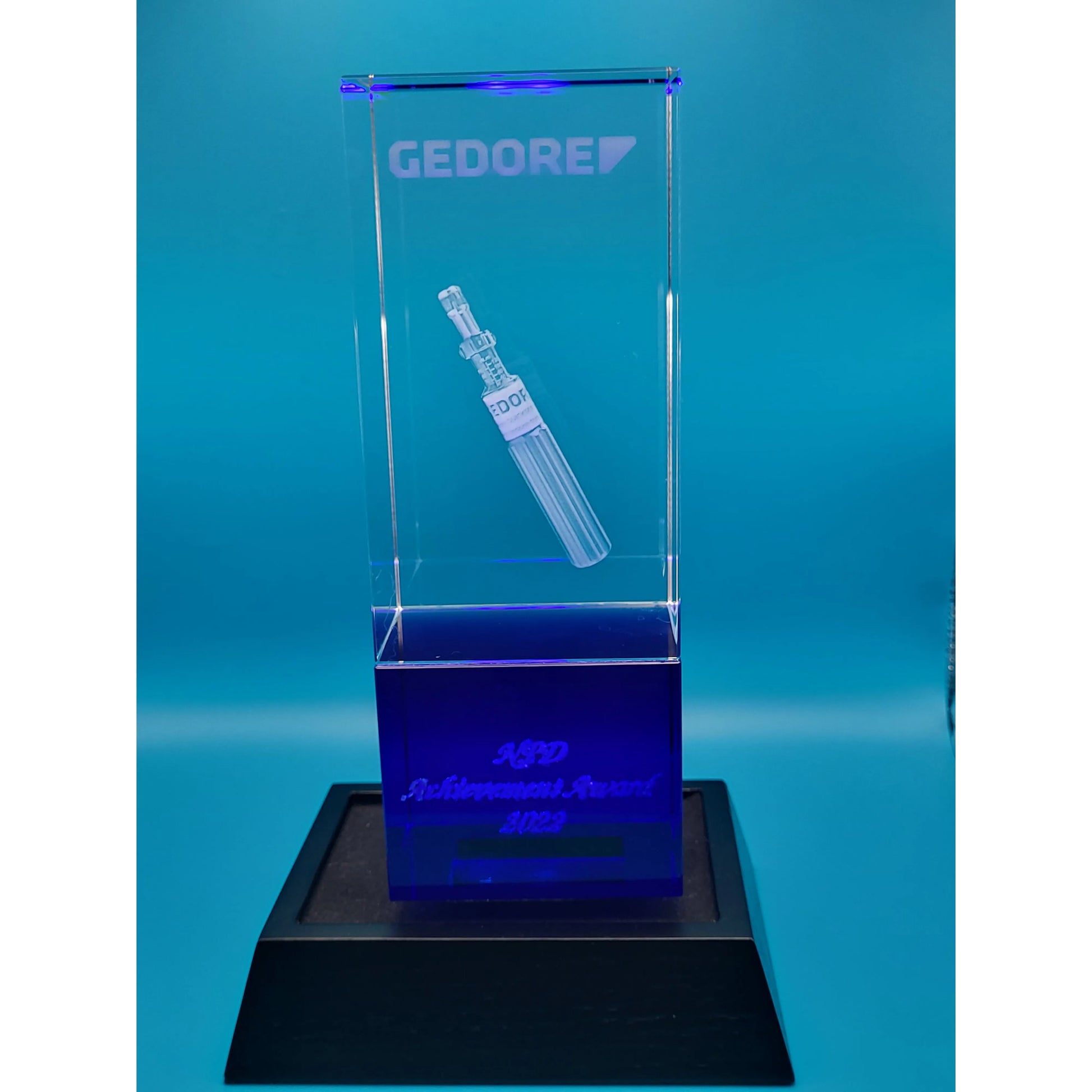 Clear glass award with engraved design  on a blue background