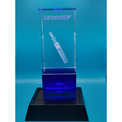 Clear glass award with engraved design  on a blue background