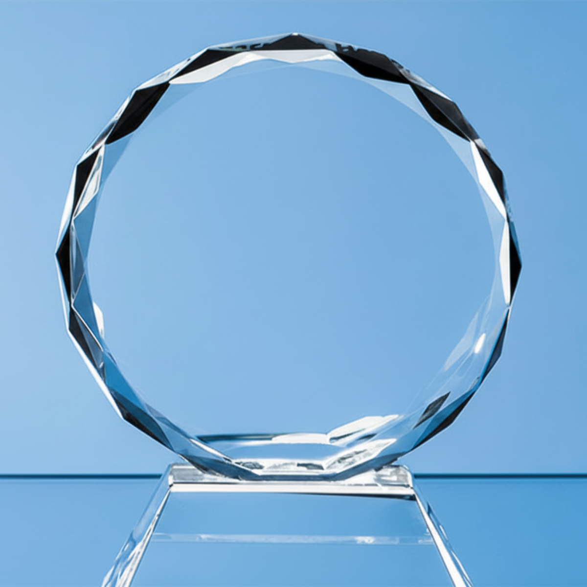 Clear circular glass award on a stand against a blue background