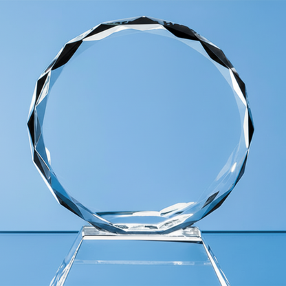 Clear circular glass award on a stand against a blue background